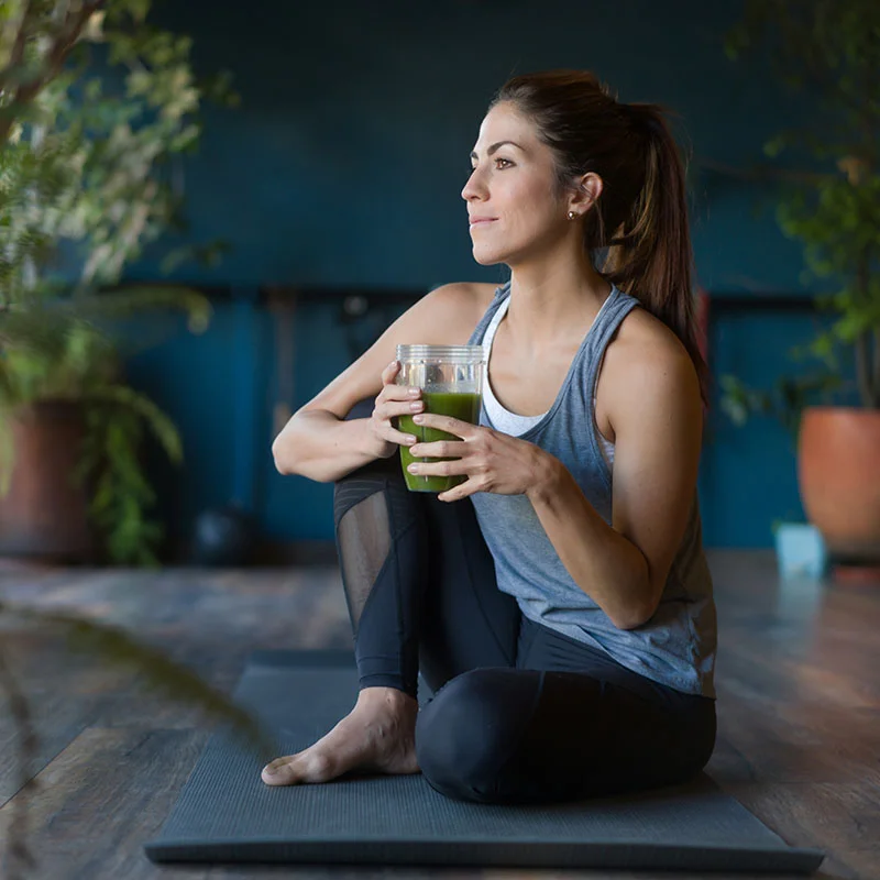 Woman having a green smoothie after yoga