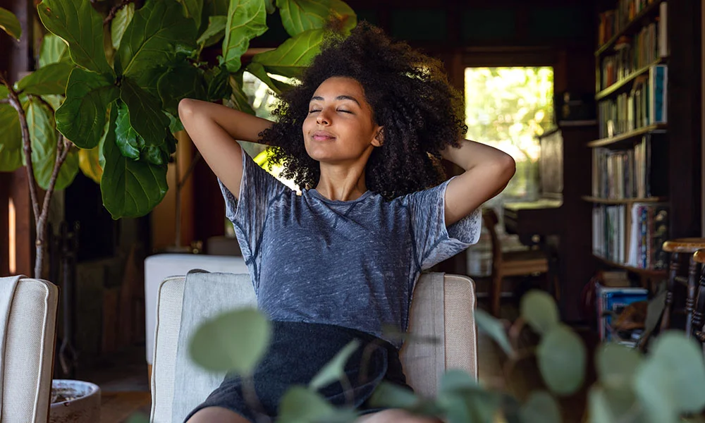 Woman relaxing in her reading den surrounded by plants